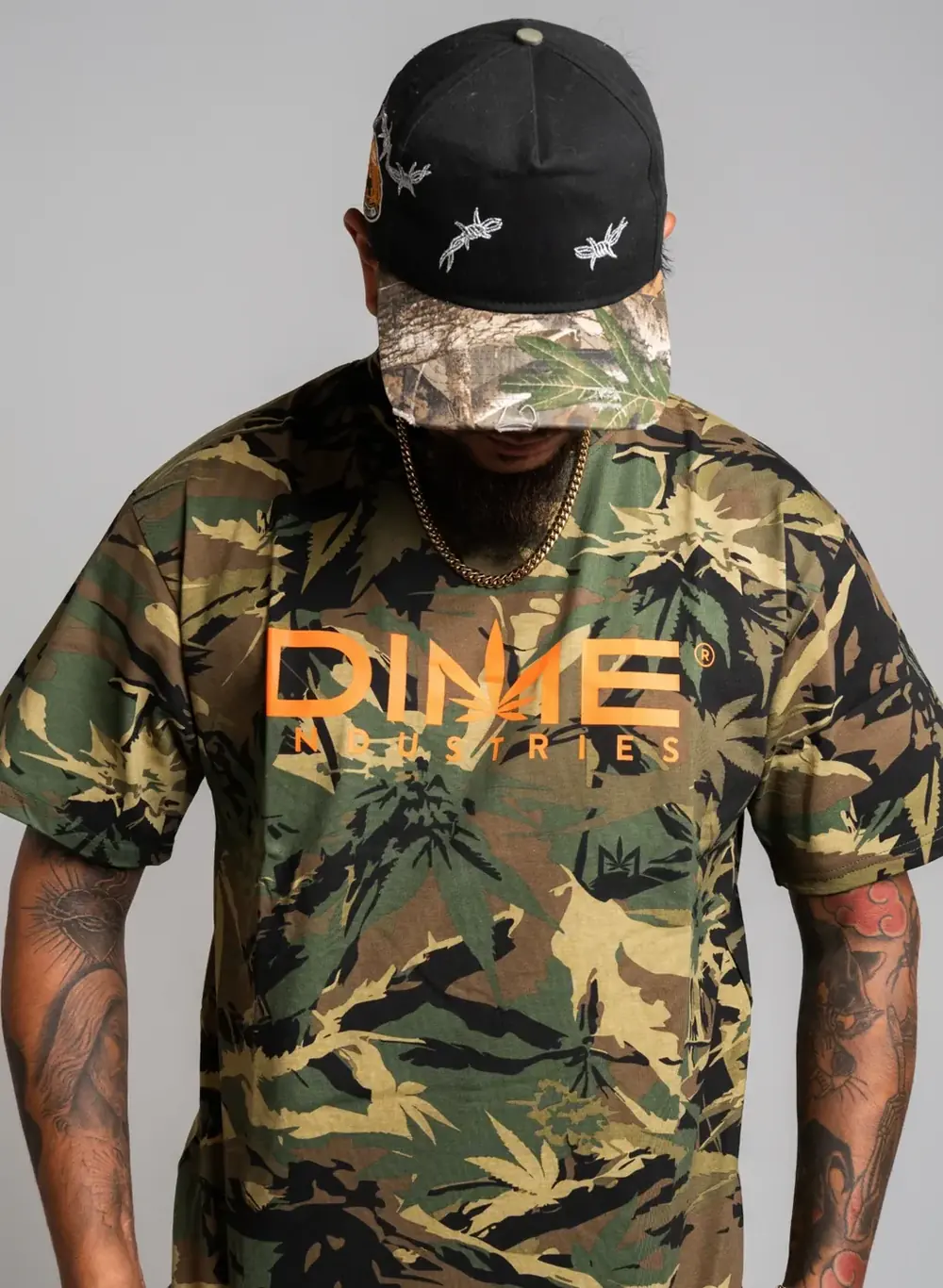 Dime Industries camo tee with orange logo worn with a barbed-wire cap