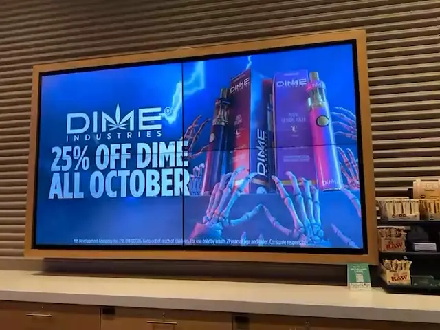Wall of in-store TV screens at Planet 13 looping Dime Industries promotions, 25% off all October
